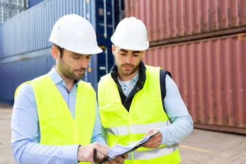 Fototapeta premium Dock worker and supervisor checking containers data on tablet