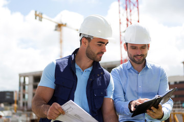 architect and worker planning meeting on construction site