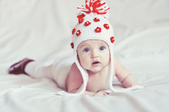 Cute little baby crawling on the bed with white knit hat on
