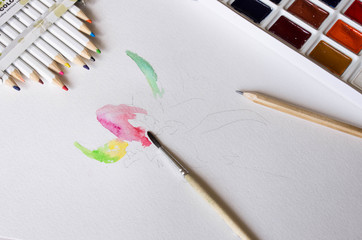Professional watercolor paints, colored pencils and brushes on a