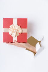 Hand holding prsent box through the hole in paper