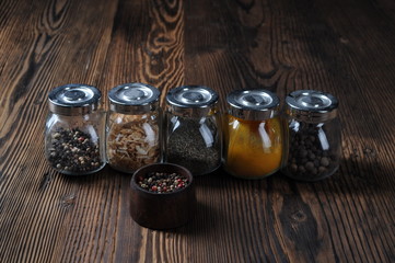 Assorted ground spices in bottles on wooden background.