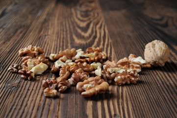 Fototapeta na wymiar Walnut kernels and whole walnut on rustic old wooden table
