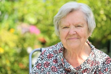 Senior woman smiling and dreaming in garden.