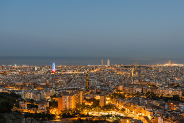 Top view and night photography from an illuminated Barcelona. The panorama shows the famous Sagrada Familia, the illuminated Torre Agbar and the Towers of the Port Olimpic until the harbor