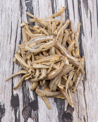 Raw anchovies over rustic wooden background