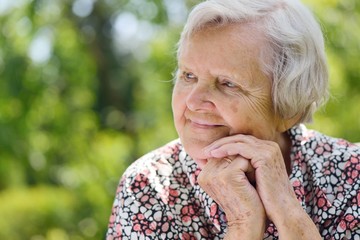 Senior woman smiling and dreaming in garden.