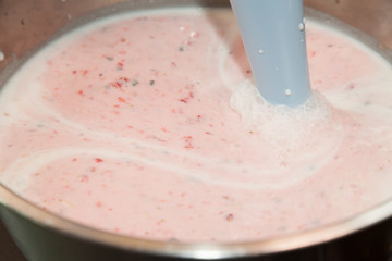 Mixing strawberry cream with milk and selective focus