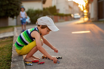 Cute little boy, playing with little toy cars on the street on s