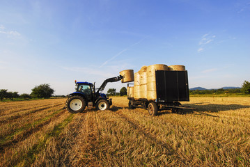 GERMANY  - Tractor impales on straw bales and loads the bales on the trailer