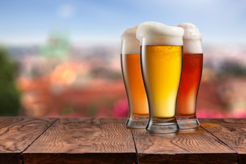 Glasses of different beer on wooden table against Prague