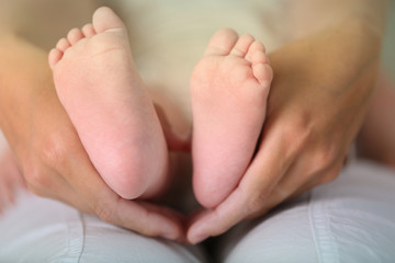 Obraz na płótnie Canvas Adult hands holding baby feet, closeup