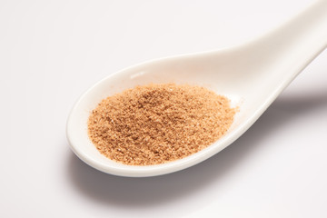 Powdered spice in white ceramic spoon on white background