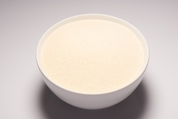 Semolina croup in white ceramic bowl on white background