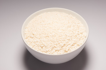 Rice flakes in white ceramic bowl on white background