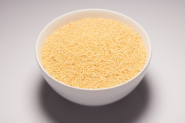 Raw organic millet croup in white ceramic bowl
