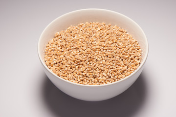 Barley in white ceramic bowl on white background