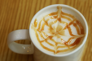 Hot caramel macchiato coffee decorated on wooden table.