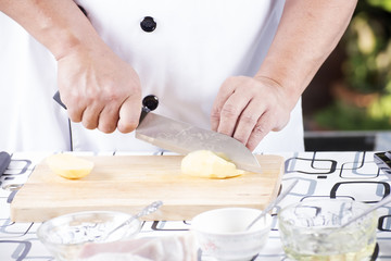 Chef cutting Potato on wooden broad