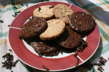 Delicious chocolate cookies on a plate with cloves