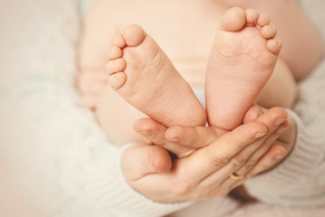 Obraz na płótnie Canvas Newborn baby feet on female hands, close-up