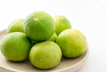 Limes on wooden dish on white background