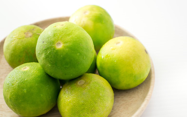 Limes on wooden dish on white background