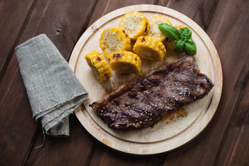 Grilled striploin steak with sliced corncob on a chopping board