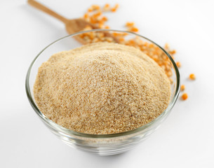 Glass bowl with flour and corn grains isolated on white