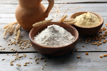 Flour in bowls with grains on wooden background