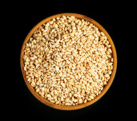 Sesame in wooden bowl, isolated on black