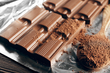 Bar of chocolate with cocoa on foil, closeup