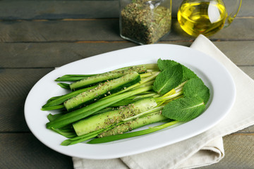 Green salad with cucumber and wild leek on wooden table, closeup