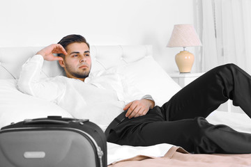 Tired man resting on bed in room