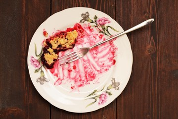 Remains of delicious cherry pie in white plate with long fork on