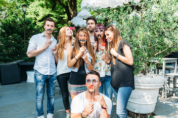 Party! A group of friends, three women and a man have fun at a party in a park with a mustache and...