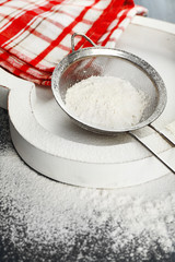 Sifting flour through sieve on wooden table, closeup