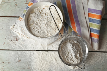 Sifting flour through sieve on wooden table, top view
