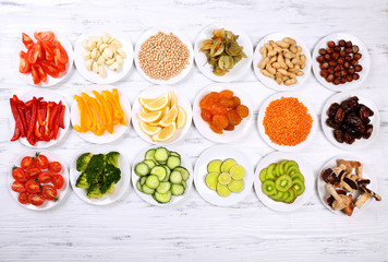 Different products on saucers on wooden table, top view