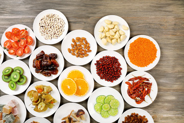 Different products on saucers on wooden table, top view