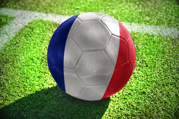 football ball with the national flag of france lies on the green field near the white line