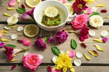 Fototapeta na wymiar Cup of herbal tea with beautiful flowers, on wooden background