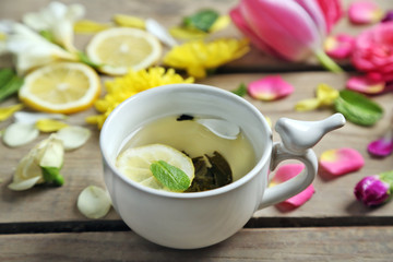 Cup of herbal tea with beautiful flowers, on wooden background