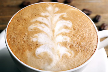 Cup of latte art coffee with grains, closeup