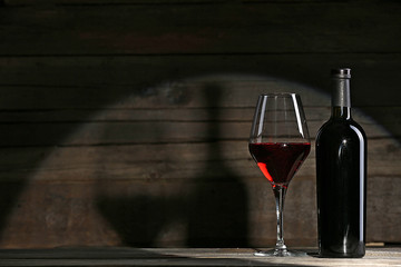 Wine bottle with glass on wooden background