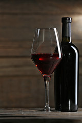 Wine bottle with glass on wooden background
