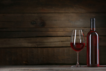 Wine bottle with glass on wooden background