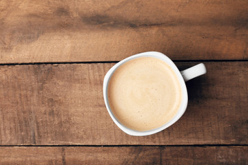 Cup of coffee on wooden table, top view