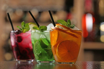 Glasses of cocktails on bar background