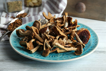 Dried mushrooms in plate on wooden table, closeup